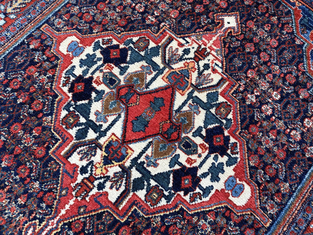 A hand - knotted antique Persian Senneh Sanandaj rug with a blue field, red border and ivory medaillon. Very good overall condition, equally even pile, fringes newly secured and original shirazi. Beautiful collectors piece, kurdish traditional carpet.