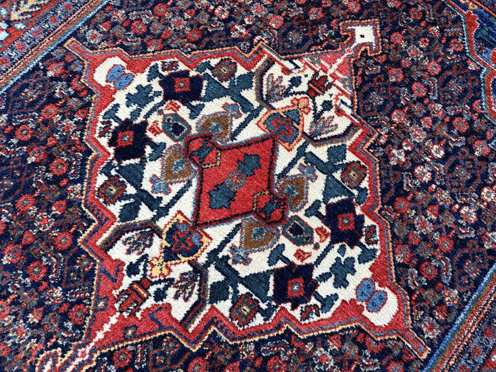 A hand - knotted antique Persian Senneh Sanandaj rug with a blue field, red border and ivory medaillon. Very good overall condition, equally even pile, fringes newly secured and original shirazi. Beautiful collectors piece, kurdish traditional carpet.